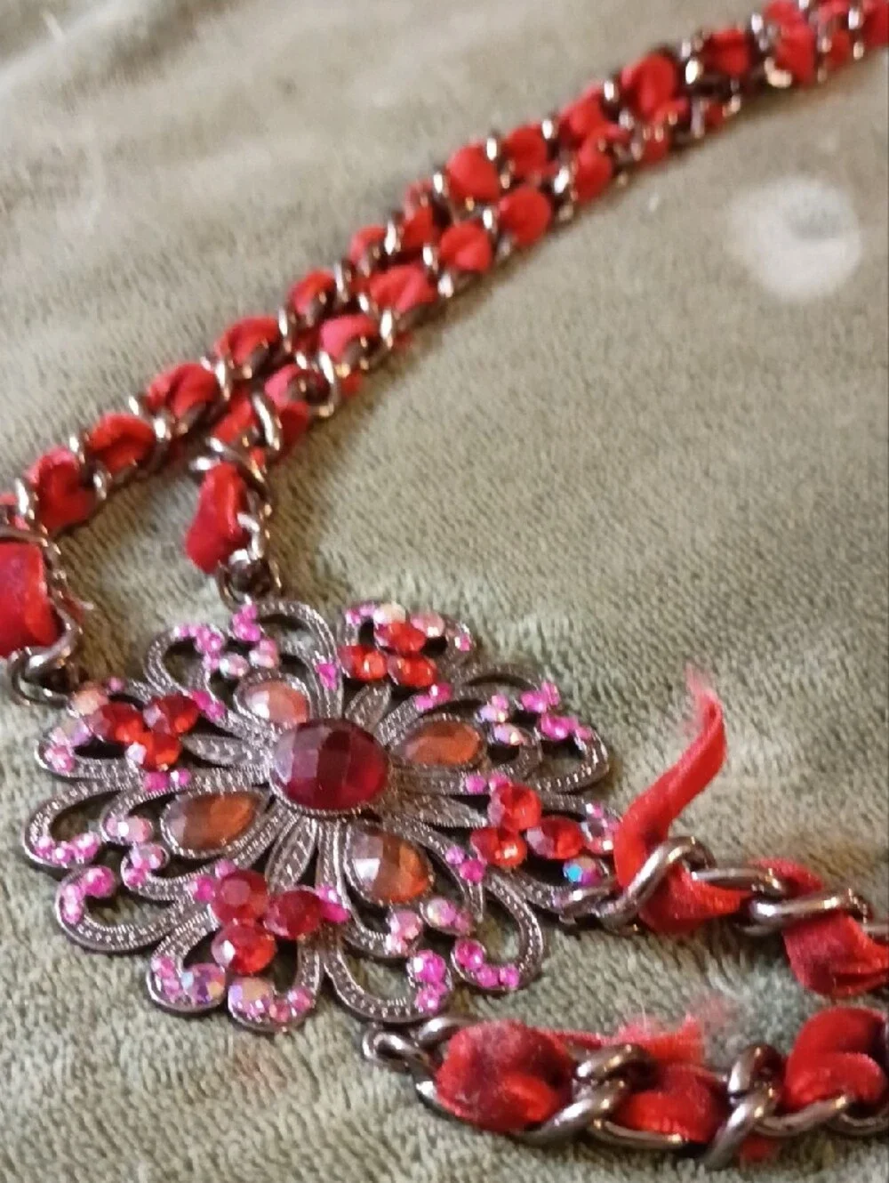 Multi Strand Necklace Featuring Interwoven Ribbon Centered Around Ornate Floral